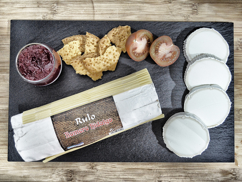 Rulo de cabra Romero Hidalgo sobre una pizarra, con rodajas de queso, tomate y mermelada