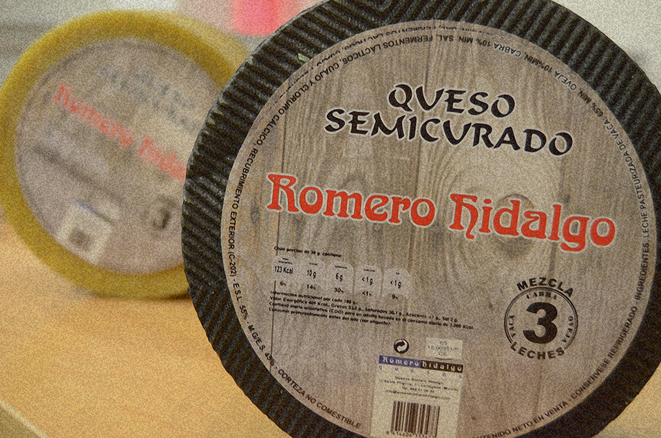 Rueda de queso semicurado Romero Hidalgo con su etiqueta, junto a otra rueda de corteza amarilla